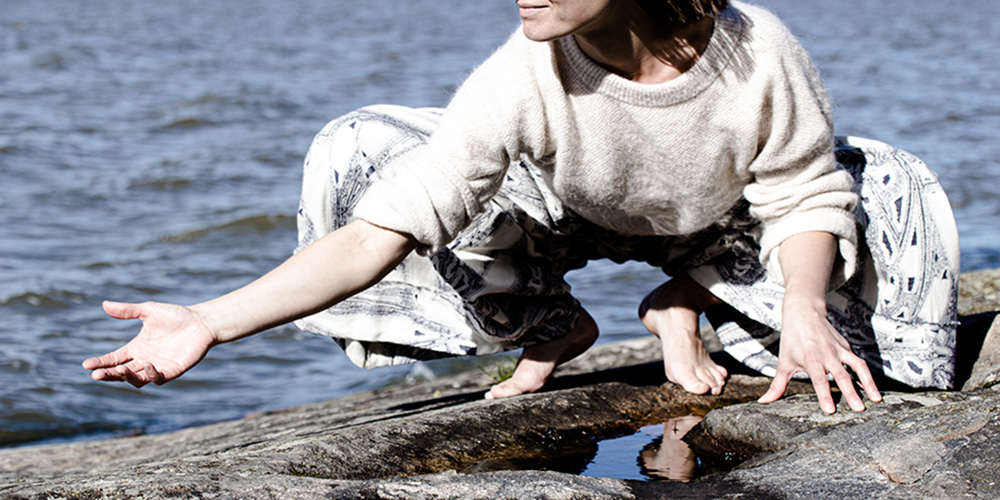 Lotta on kyykyssä rantakalliolla ja taustalla näykyy vettä