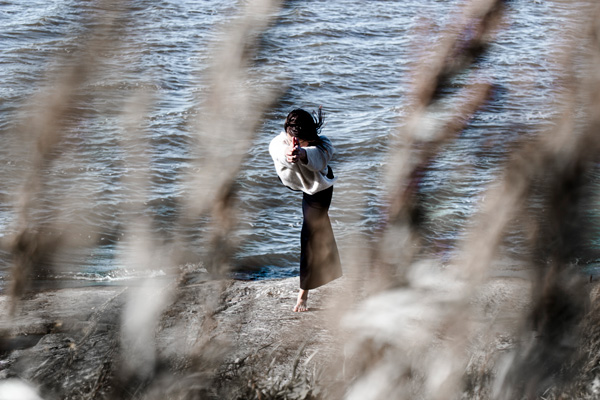 jooga soturi kolme asana veden rannalla kalliolla